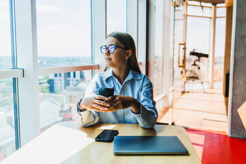 A thoughtful young professional is situated in a modern workspace, fully engaged while manipulating both a smartphone and a laptop, embodying the essence of productivity and innovation