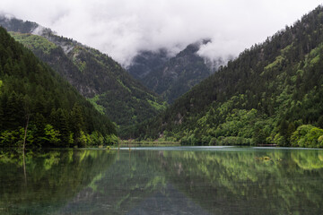 Jiuzhaigou, China: Dramatic reflection of the forest in the clear water of the Mirror lake in the Jiuzhaigou scenic area on a cloudy spring day in Sichuan, Southwest China