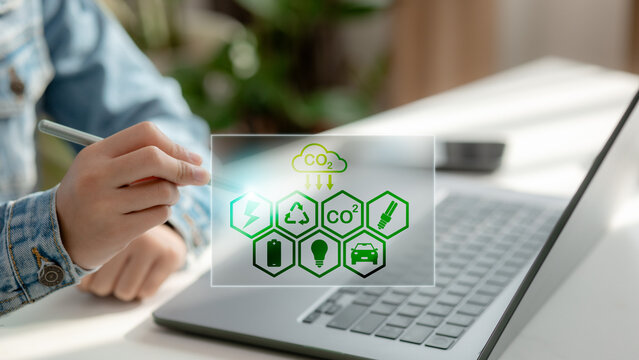 Hand using stylus with icons of CO2 emission, renewable energy, recycling, and electric vehicle. Concept of carbon footprint management, green technology, and sustainability analytics. - Powered by Adobe