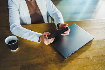 In a modern workspace, a focused professional woman adeptly uses her smartphone and laptop while enjoying coffee, highlighting her impressive multitasking skills in todays fastpaced work life