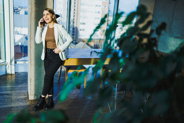 A young, ambitious businesswoman is engaged in a crucial phone call in a bright, modern office...