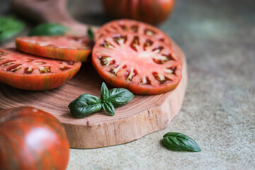 Close-up of vibrant sliced tomatoes with fresh basil on rustic wooden cutting board, ready for meal