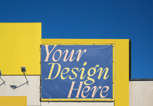 A blank advertising space mounted on a vibrant yellow wall against a clear blue sky