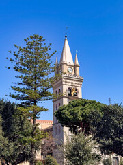 The clock tower stands majestically in the foreground, adorned by tall trees and vibrant foliage...