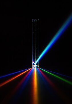 A prism demonstrating the dispersion of light into red, green, and blue components against a dark background.