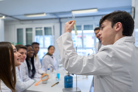 Chemistry student holding test tube observing chemical reaction in laboratory - Powered by Adobe