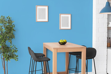 Dining table and chairs near light blue wall in room. Interior design