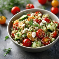 Fresh colorful vegetable salad with cherry tomatoes cucumbers herbs feta cheese and quinoa in a white bowl on dark background Healthy vegetarian dish