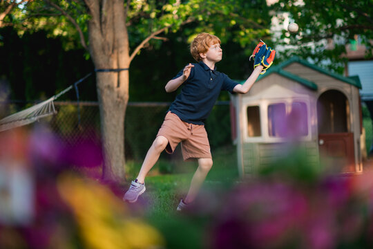 Young boy focuses while catching ball during outdoor backyard play