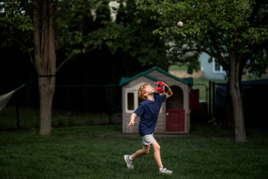 Young boy focuses while catching ball during outdoor backyard play