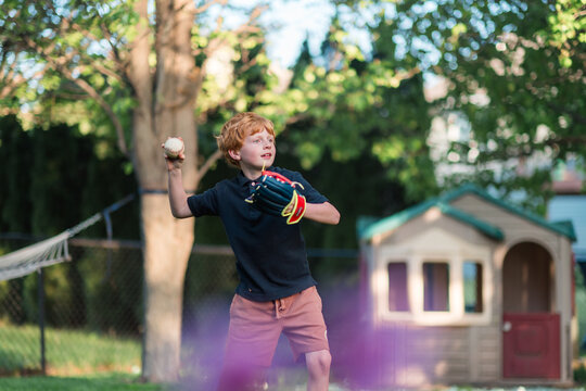 Young boy throws baseball during outdoor backyard play