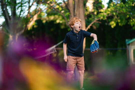 Young boy catches hard ball during outdoor backyard play