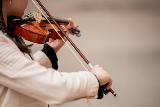 Close-up of a classical violin and a child's hand with a bow.