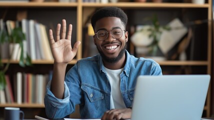 Person using laptop in a home office setting waves hello in a friendly gesture