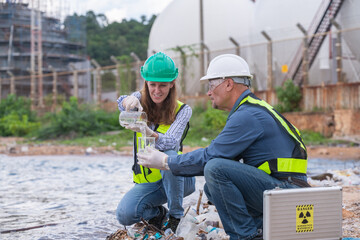 Environmental engineer or workers examining waste water along a large industrial waste water or...