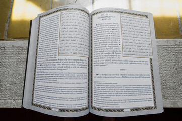 Otwarte strony religijnej księgi Koranu z tekstem arabskim i tłumaczeniem na język europejski.