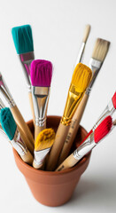 Fototapeta premium Colorful paintbrushes in terracotta pot, showcasing art supplies, creativity and hobby concept