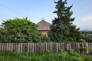 Old rustic wooden house behind the fence