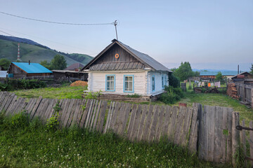 Old rustic wooden house behind the fence