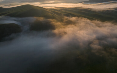 Aerial drone view of foggy sunrise over hills