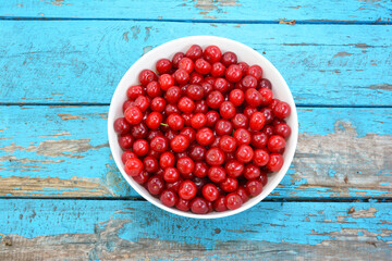 Organic superfoods - red cherries. Bowl with red juicy ripe cherries on a blue wooden background.