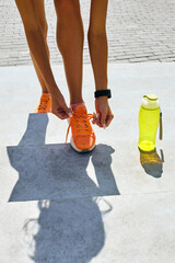 Fit woman tying up laces on her sport shoes