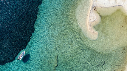 Motorboat sailing near white sand coast in Syvota, Greece, aerial view