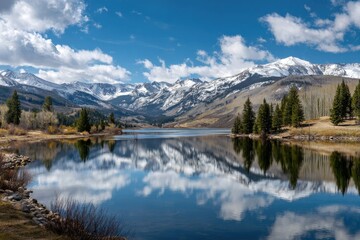 A tranquil mountain lake mirrors a stunning sky, snow-capped peaks, and lush greenery along its shores, showcasing a serene, natural landscape