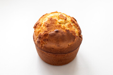 Muffin lies on a white surface. The muffin is golden brown and has a slightly crispy texture. Homemade baking and pastry made from wheat flour. Making bread and Easter cakes