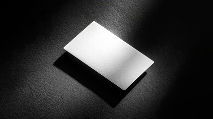 Blank white business card on dark textured surface.
