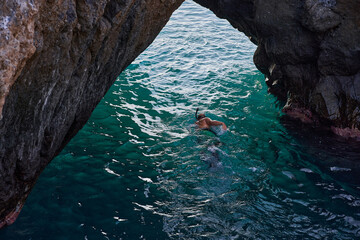 Snorkeler passing through volcanic arch