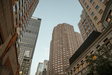 Tall residential and office buildings rise into the sky in a dense urban area. The warm evening light highlights the architectural variety and geometric windows.