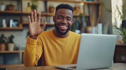 Man waves hello while working on a laptop in a cozy, plant-filled environment during home office hours