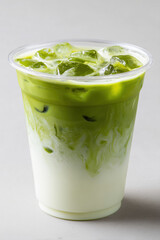 Refreshing Iced Matcha Latte with Milk in a Clear Plastic Cup on White Background