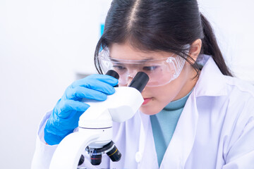 Teen girl observing a sample under the microscope during experiment. Science, laboratory,...