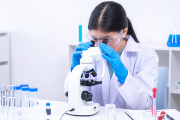 Teen girl observing a sample under the microscope during experiment. Science, laboratory,...