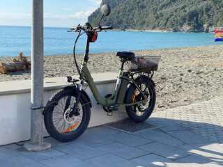 Electric bicycle strapped near pole on beach. Innovation and alternative energy. Tourism and...