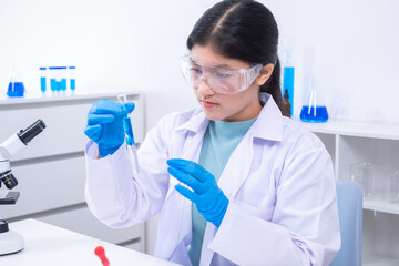 Young girl lifting glass tube and inspecting blue liquid inside. Science, laboratory, scientist,...