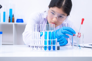 Teen scientist girl conducting science test by carefully evaluating blue solution in laboratory....