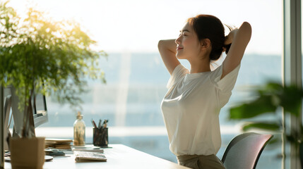 Young Woman Stretching at Desk in Bright Modern Office with Green Plants and Natural Light