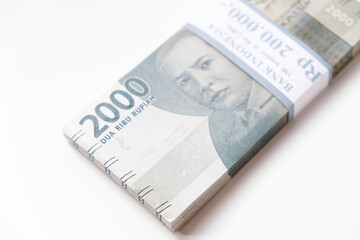 A stack of Indonesian rupiah Rp 2.000 banknotes isolated on white background for THR on Eid al-Fitr or Lebaran days