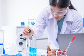 Teen scientist girl conducting science test by carefully evaluating blue solution in laboratory....