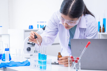 Teen scientist girl conducting science test by carefully evaluating blue solution in laboratory. Science, laboratory, experiment, and research demonstrate academic progress and practical skills.