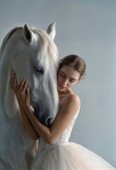 Graceful ballerina in a white lace dress embracing a white horse in a soft, cinematic studio setting. Empathy, artistic white background.