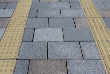 Gray and brown pavement with yellow tactile tiles for blind handicap. Yellow tactile paving on...