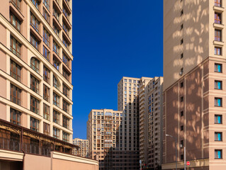 City view on a sunny day. Modern building and houses against the blue sky.