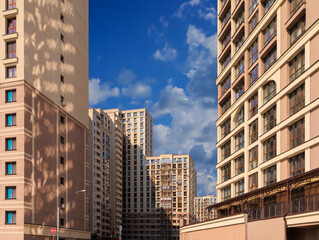 City view on a sunny day. Modern building and houses against the blue sky.