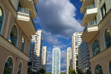 City view on a sunny day. Modern building and houses against the blue sky.
