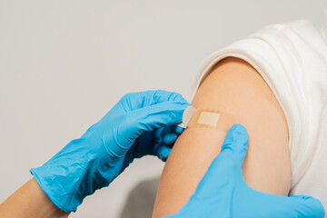 Doctor hands putting the bandage after giving vaccine against COVID-19