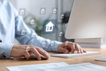 Real estate agent looking for housing on computer, closeup. Illustrations of buildings over desk